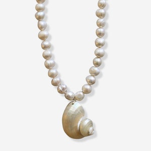 May include: A white pearl necklace with a large seashell pendant.