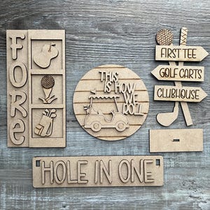 May include: Wooden golf-themed signs with the words "FORE", "This is how we roll", "First Tee", "Golf Carts", "Clubhouse", and "Hole in One".