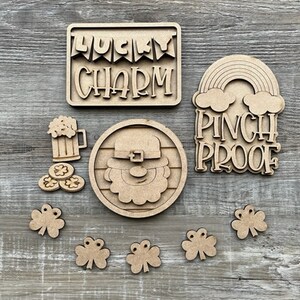 May include: A collection of unfinished wooden St. Patrick's Day decorations. Includes a sign that says "Lucky Charm", a rainbow with "Pinch Proof", a leprechaun, beer mug, gold coins, and shamrocks. Perfect for DIY crafts and festive decor.