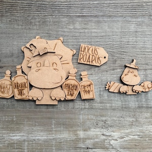 May include: Wooden Halloween-themed cutouts featuring a rhino wearing a witch hat, bottles labeled "Veloc Venom" and "Jubbesic Juice", and a tag that says "Hocus Roarus". A smaller rhino cutout is also present.