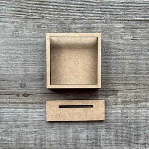 May include: Two unfinished wooden boxes, one with a rectangular opening and the other with a slot. The boxes are on a woodgrain background.