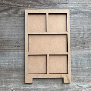 May include: A light brown, unfinished wooden shelf with multiple rectangular compartments. The shelf has a simple design with a rectangular frame and various sized openings, perfect for displaying small items or organizing. The shelf is set against a wooden background.