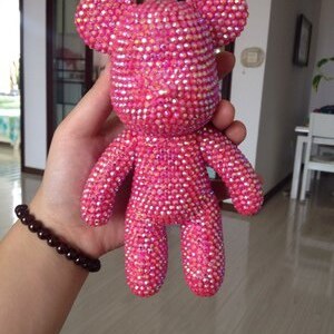Op de afbeelding: Een roze teddybeer bedekt met iriserende strass steentjes. De beer heeft een eenvoudig ontwerp zonder extra kenmerken.