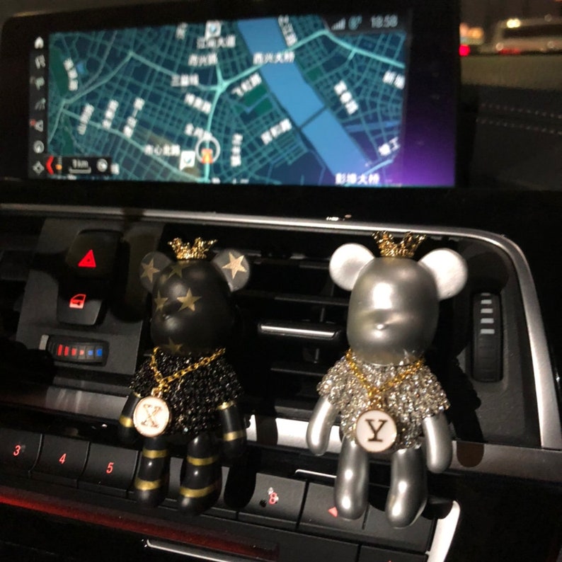 May include: Two car air fresheners shaped like bears wearing gold chains and crowns. The bear on the left is black with gold stars and a gold 'X' pendant. The bear on the right is silver with rhinestones and a gold 'Y' pendant.
