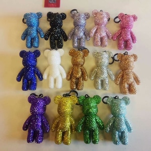 Pode incluir: Conjunto de 14 pequenos chaveiros de urso de pelúcia com strass brilhantes em várias cores, incluindo azul, verde, dourado, prateado, roxo, rosa, branco e preto.