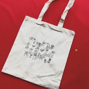 May include: A white canvas tote bag with black line drawings of various dog breeds. The bag has two long handles.
