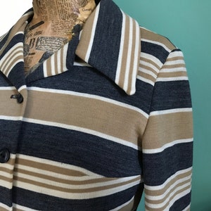May include: A striped long-sleeved jacket with a collar. The jacket is brown, white, and dark blue.