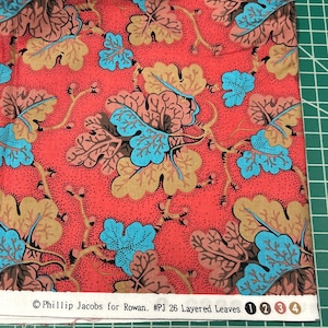 May include: Red fabric with a repeating pattern of blue, brown, and tan leaves. The fabric has a small white label with the text "Phillip Jacobs for Rowan. #PJ 26 Layered Leaves 1 2 3 4".
