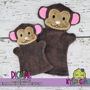 May include: Two brown monkey hand puppets with tan faces and pink ears. The puppets have embroidered details and are made of a soft, textured material. The text "DIGITAL MACHINE EMBROIDERY DESIGN" is visible at the bottom.