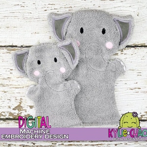 May include: Two grey elephant hand puppets with black eyes and pink cheeks. The puppets have grey ears with darker grey trim. The text "DIGITAL MACHINE EMBROIDERY DESIGN" is displayed in a purple box. The puppets are on a white wooden surface.