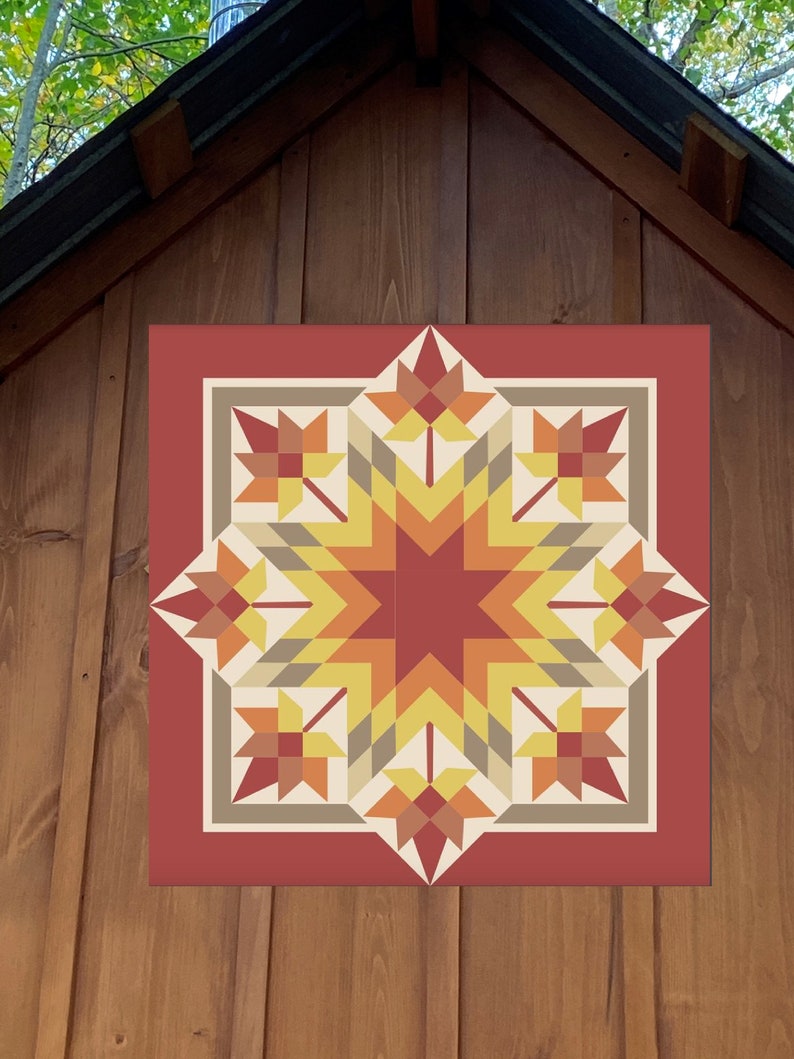May include: A geometric quilt design featuring a central eight-pointed star in shades of yellow, orange, and red, surrounded by stylized leaf shapes. The quilt is framed by a red border and set against a wooden background.