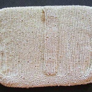 May include: A white beaded clutch bag with a small opening at the top.