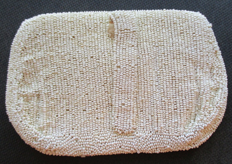 May include: A white beaded clutch bag with a small opening at the top.