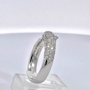 May include: A white gold ring with a pave diamond panther head design. The ring is engraved with 'Cartier 950 18K 002828'.