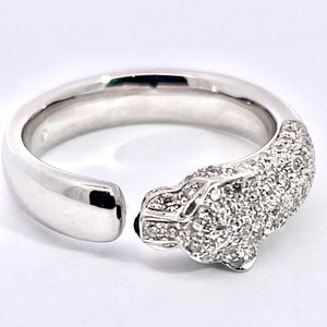 May include: A white gold ring with a diamond-encrusted panther head design. The ring is open on one side and the panther head is facing the right side of the image.