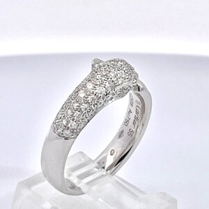 May include: A silver diamond panther ring. The ring is set with pave diamonds and has the inscription 'Cartier 58 41750' on the inside of the band.