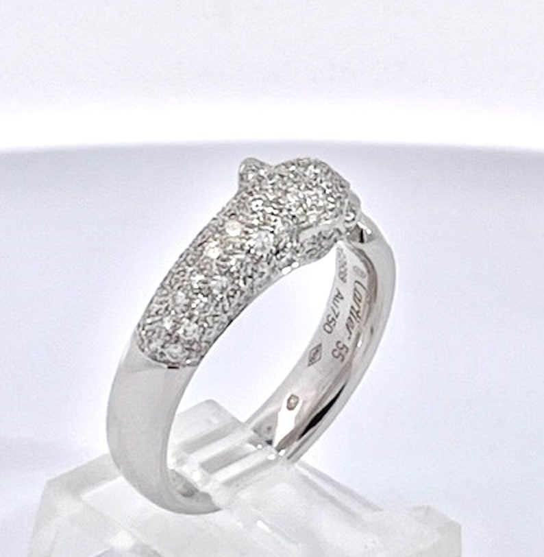 May include: A silver diamond panther ring. The ring is set with pave diamonds and has the inscription 'Cartier 58 41750' on the inside of the band.