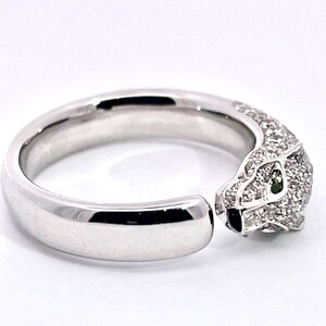 May include: A white gold ring with a pave diamond panther head design. The panther's eyes are set with green gemstones.