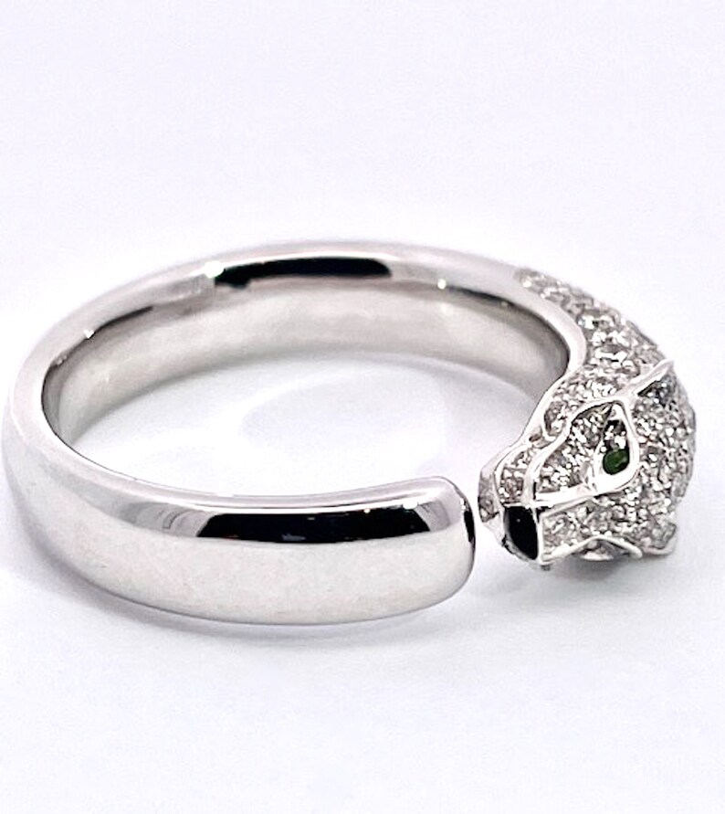 May include: A white gold ring with a pave diamond panther head design. The panther's eyes are set with green gemstones.