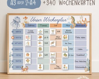 May include: A framed weekly planner with a light wood border. The planner features a blue and beige color scheme with illustrations of sea creatures. Text includes "Unser Wochenplan" and days of the week.