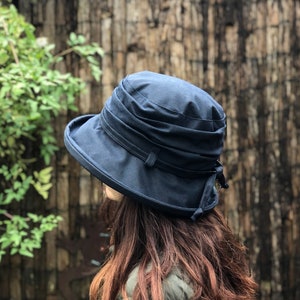 May include: A dark blue, wide-brimmed hat with a folded crown. The hat is made of a soft, textured fabric and has a simple, elegant design.