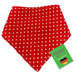 Può includere: Un bavaglino rosso per bambini, stile bandana, con pois bianchi. Il bavaglino ha un bordo morbido e sfocato. Un'etichetta dice "Dimples Sew Happy" e "Made in Germany."