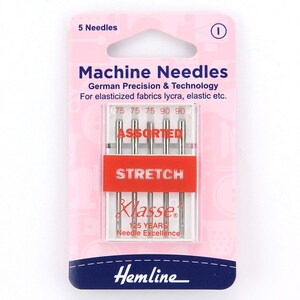 Könnte beinhalten: Eine Packung mit 5 sortierten Stretch-Nähmaschinennadeln zum Nähen. Die Nadeln befinden sich in einem durchsichtigen Kunststoffbehälter mit einem roten Etikett, auf dem "Stretch" und "Sortiert" steht. Die Packung ist mit "Hemline" und "Klasse 125 Years Needle Excellence" gekennzeichnet.