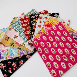May include: A collection of 12 fabric squares featuring a variety of floral patterns in pink, red, blue, and brown. The squares are arranged in a fan shape, with the largest square at the bottom and the smallest square at the top.