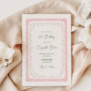May include: A white invitation card with a pink scalloped border and floral accents. The text reads "2nd Birthday" and includes details for Elizabeth Baker's birthday on January 13th, 2027, at 1:00 PM, with an address and RSVP information.