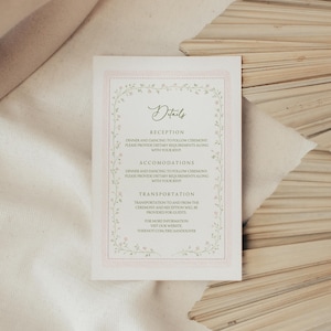 May include: A rectangular wedding details card with a pink border and floral accents. The card features the word "Details" in elegant script, followed by sections for reception, accommodations, and transportation information. The website address is also included.