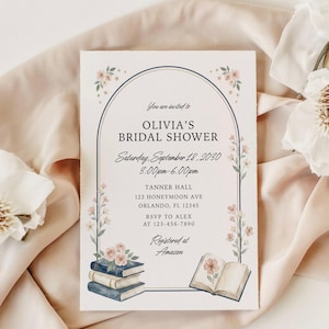 May include: A rectangular bridal shower invitation card featuring a dark blue arched frame decorated with pink floral illustrations, a stack of three books with pink roses on top, and an open book with a flower illustration, with printed text.