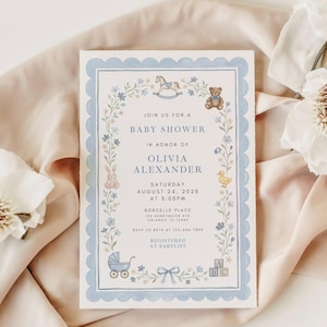 May include: Baby shower invitation with a blue scalloped border and floral accents. The invitation includes the text "Join us for a Baby Shower" and details for Olivia Alexander's baby shower, including the date, time, and location.
