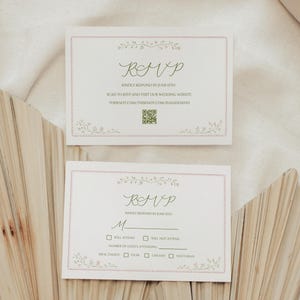 May include: Two RSVP cards with floral accents and a pink border. The cards feature the word "RSVP" in elegant script, along with instructions to respond by June 15th. The cards also include a QR code and a website address.