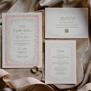 May include: A wedding invitation suite comprising an invitation, RSVP card, and details card. The cards have a pink scalloped border and floral detailing. The main invitation includes the names Elizabeth Williams and David Jason, plus the wedding date and time.
