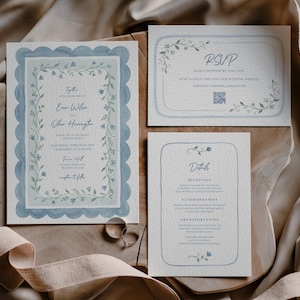 Puede incluir: Juego de invitaciones de boda con una invitación principal, una tarjeta RSVP y una tarjeta de detalles. La papelería tiene un borde festoneado azul claro y detalles florales. La invitación principal incluye los nombres Erin Wilson y Oliver Harrington.