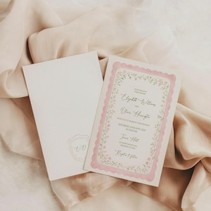 May include: Wedding invitation with a floral border and pink accents. The invitation includes the names Elizabeth Williams and Oliver Harrington, along with the date and time of the event. An envelope with a matching design is also present.