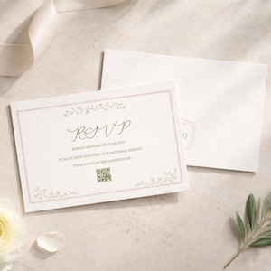 May include: An RSVP card with a floral border and elegant script, alongside a matching envelope. The card reads "RSVP" and includes instructions to respond by June 15th and a website address. Soft lighting and floral accents create a romantic ambiance.