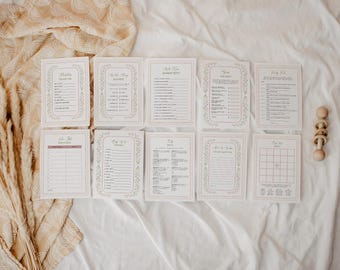 May include: A set of ten rectangular baby shower game cards with white backgrounds, thin pink borders, and delicate floral illustrations. Each card features printed text, lines for writing, and checkboxes for various activities and trivia.