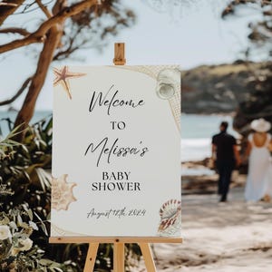 Peut inclure: Une pancarte d'accueil blanche avec un motif de coquillages et d'étoiles de mer. La pancarte indique "Bienvenue à la Baby Shower de Melissa le 12 août 2024".