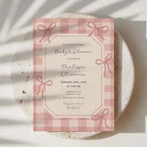 May include: A baby shower invitation with a pink gingham pattern and decorative bows. The invitation includes the text "Baby Shower" and details for Melissa Oliveria's baby shower on January 13th, 2026.