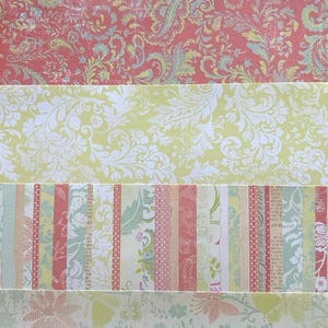 May include: A collection of five horizontal strips of decorative paper featuring various patterns. The designs include floral motifs in pink and green, a red paisley print, a yellow damask pattern, and a vertical striped section with text.