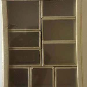 May include: A rectangular, multi-compartment storage box with a clear front. The box is tan with a grid of small, square compartments. The text "TIM HOLTZ CONFIGURATIONS" and "idea-ology" are visible. Dimensions are 6.75 x 8.75 inches.