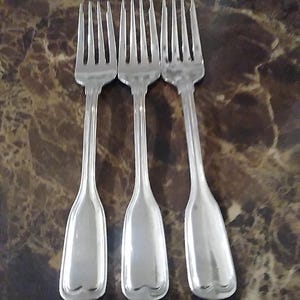 May include: Three silver forks with ornate handles. The forks are arranged in a row, with the tines facing up.