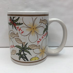 May include: White ceramic mug with a brown rim and a design of palm trees, fish, and flowers. The words "Aloha" and "Hawaii" are written in red on the mug.