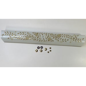 May include: A white, rectangular light fixture with a gold floral design. The fixture is accompanied by several small, round mounting hardware pieces in black and gold.