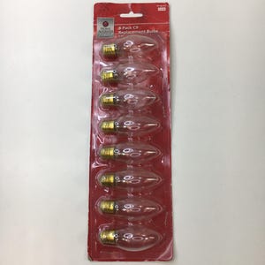 May include: A red packet containing eight clear C9 replacement bulbs. Each bulb has a teardrop shape and a gold-coloured base. The packaging features the text "Home Accents Holiday" and "8-Pack C9 Replacement Bulbs."