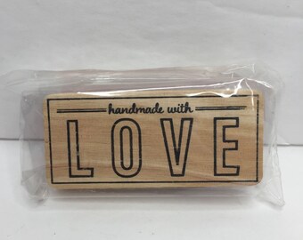 Könnte beinhalten: Ein Stempel aus Holz mit dem Text "handmade with LOVE" in schwarzen Buchstaben.