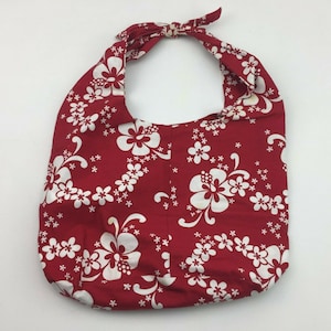 Könnte beinhalten: Rote Stofftasche mit weißem Blumenmuster. Die Tasche hat einen geknoteten Henkel und ist aus weichem, leichtem Material.