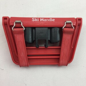 May include: Red plastic ski handle with black straps and metal clips. The handle has the words "Ski Handle" printed on the top and "Made in Hong Kong" printed on the side.
