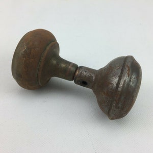 May include: A pair of antique door knobs made of metal with a rusty finish. The knobs are round and have a simple design.